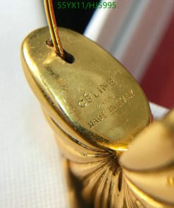 Close-up of Celine gold loafer's buckle detail.