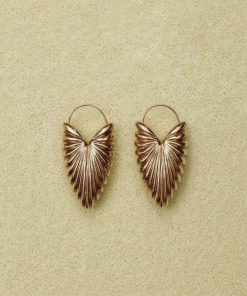 Gold leaf design earrings on beige background.