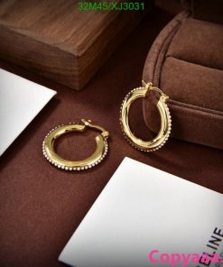 Gold hoop earrings with pearls on brown velvet surface.