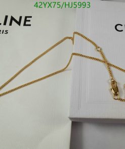 Gold cross necklace on white Celine box.