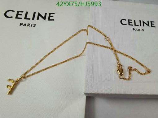 Gold cross necklace on white Celine box.