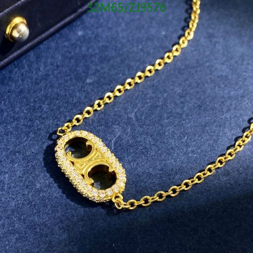 Gold necklace with diamond pendant on blue background.