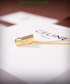 Gold Celine pendant on white surface.