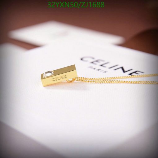 Gold Celine pendant on white surface.