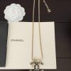 Chanel logo pendant necklace on book with white flower.