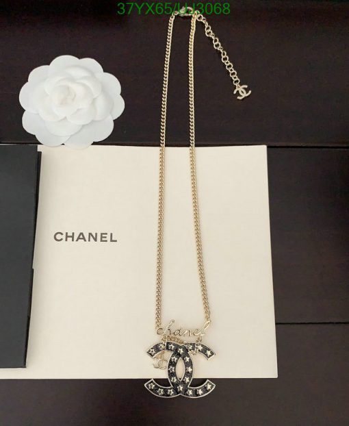 Chanel logo pendant necklace on book with white flower.