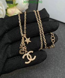 Gold pendant necklace on black glove.