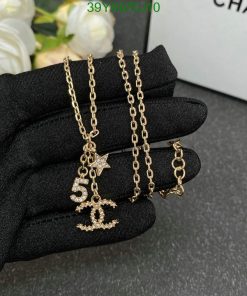 Gold pendant necklace on black glove.