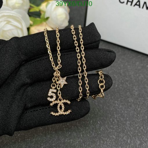 Gold pendant necklace on black glove.