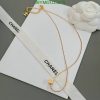 Gold necklace on white Chanel envelope with ribbon.