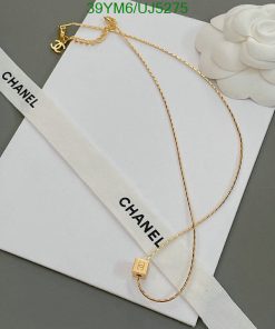 Gold necklace on white Chanel envelope with ribbon.