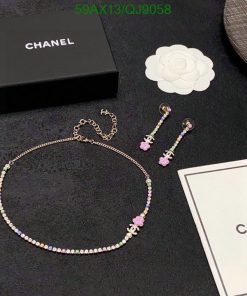 Chanel jewelry set with necklace and earrings on dark background.