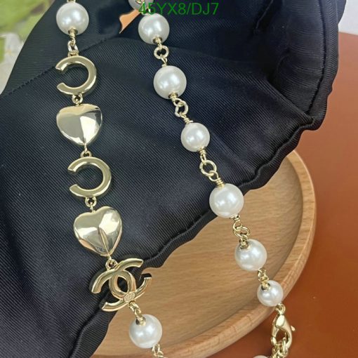 Elegant pearl and gold charm bracelet on black fabric.