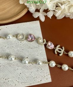 Pearl and pink gemstone gold bracelets on stylish background.