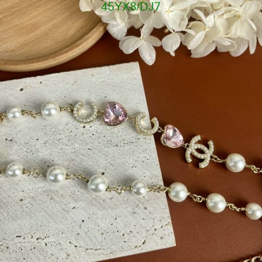 Pearl and pink gemstone gold bracelets on stylish background.