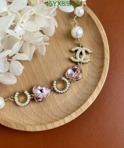 Pearl and gemstone bracelet on wood with flowers.