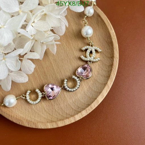 Pearl and gemstone bracelet on wood with flowers.