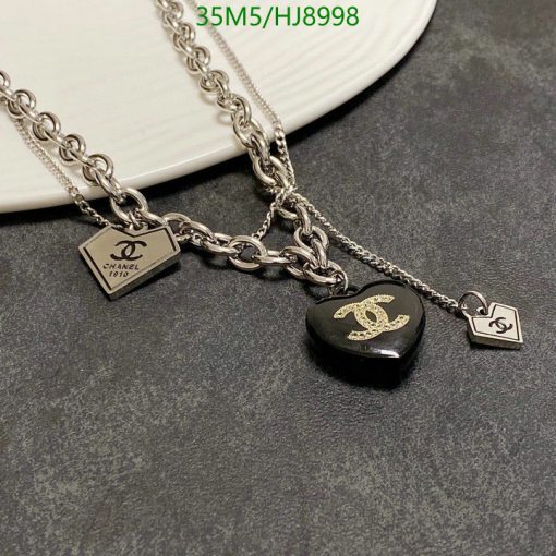 Designer chain necklace with logo charms on plate.