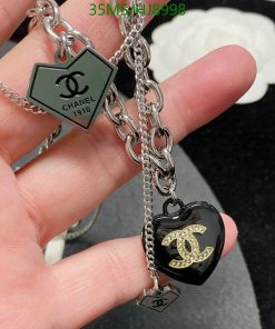 Chanel branded heart-shaped charms and chain on person's hand.