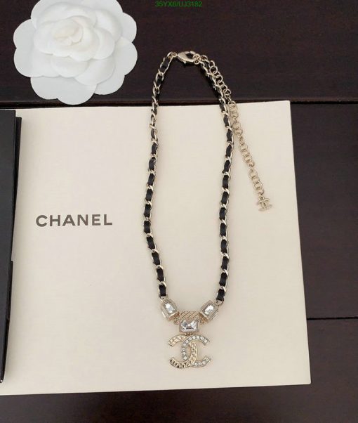 Chanel branded necklace with pendant on book.