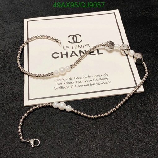 Chanel pearl bracelet with guarantee certificate on black background.