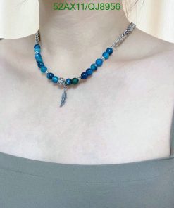 Woman wearing a blue beaded necklace with feather charm.