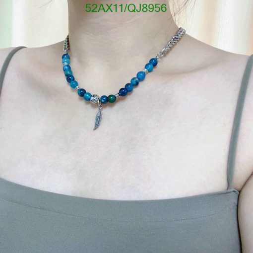 Woman wearing a blue beaded necklace with feather charm.