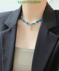 Woman wearing turquoise beaded necklace with silver charm.