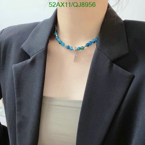 Woman wearing turquoise beaded necklace with silver charm.