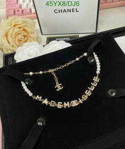 Chanel pearl necklace with logo on black velvet background.