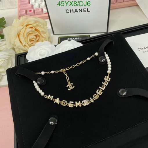 Chanel pearl necklace with logo on black velvet background.