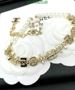 Designer gold chain bracelet with white floral detail.