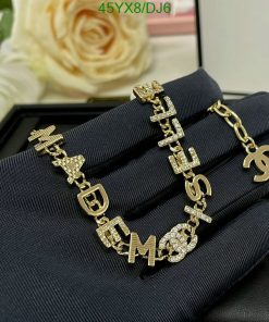 Gold designer letter bracelet with diamonds on black surface.