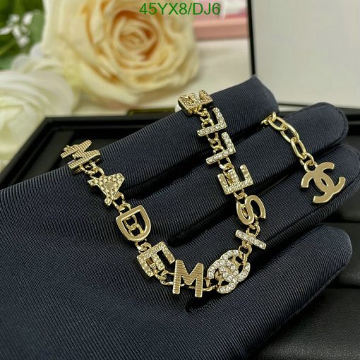 Gold designer letter bracelet with diamonds on black surface.