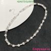 Elegant pearl and silver bead necklace on dark surface.