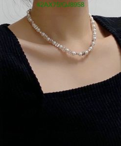 Woman wearing pearl necklace, black top.