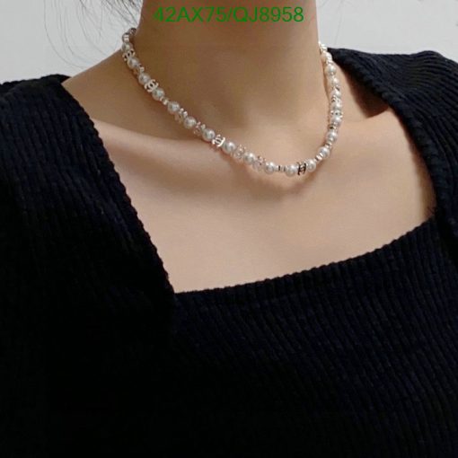 Woman wearing pearl necklace, black top.