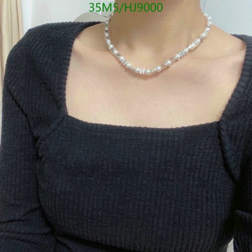 Woman wearing black sweater and pearl necklace.