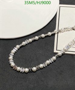 Pearl necklace with silver accents on dark background.