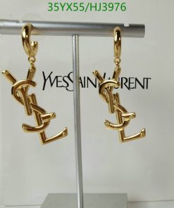 Gold designer logo earrings on display stand.