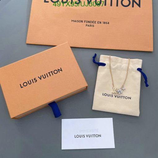 Luxury branded packaging and jewelry on gray surface.