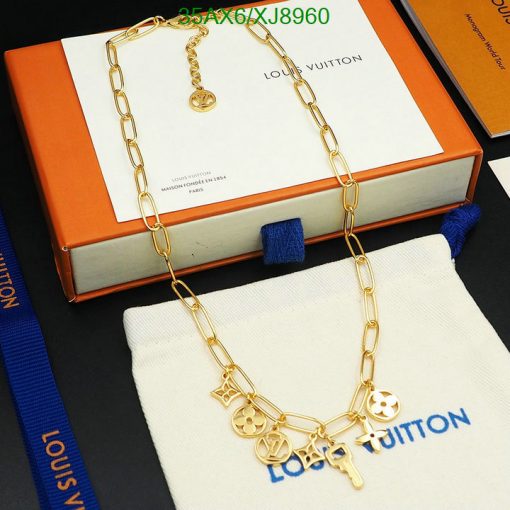 Gold charm necklace on packaging with brand logo.