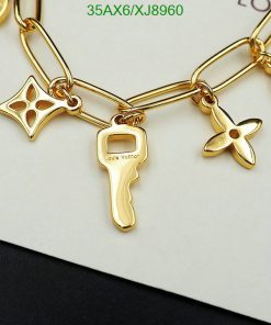 Gold charm bracelet with designer label and shapes.