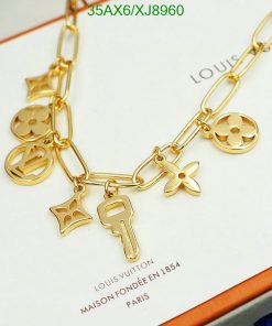 Gold charm bracelet with iconic symbols on brand background.