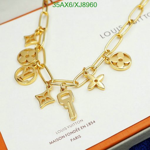 Gold charm bracelet with iconic symbols on brand background.