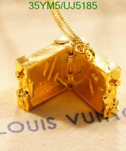 Gold designer suitcase pendant necklace on fabric.