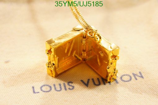 Gold designer suitcase pendant necklace on fabric.