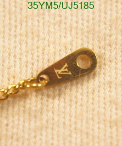 Gold chain tag with engraved letter on fabric.