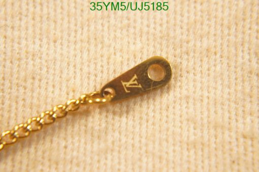 Gold chain tag with engraved letter on fabric.