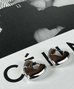 Silver heart-shaped earrings on graphic background.